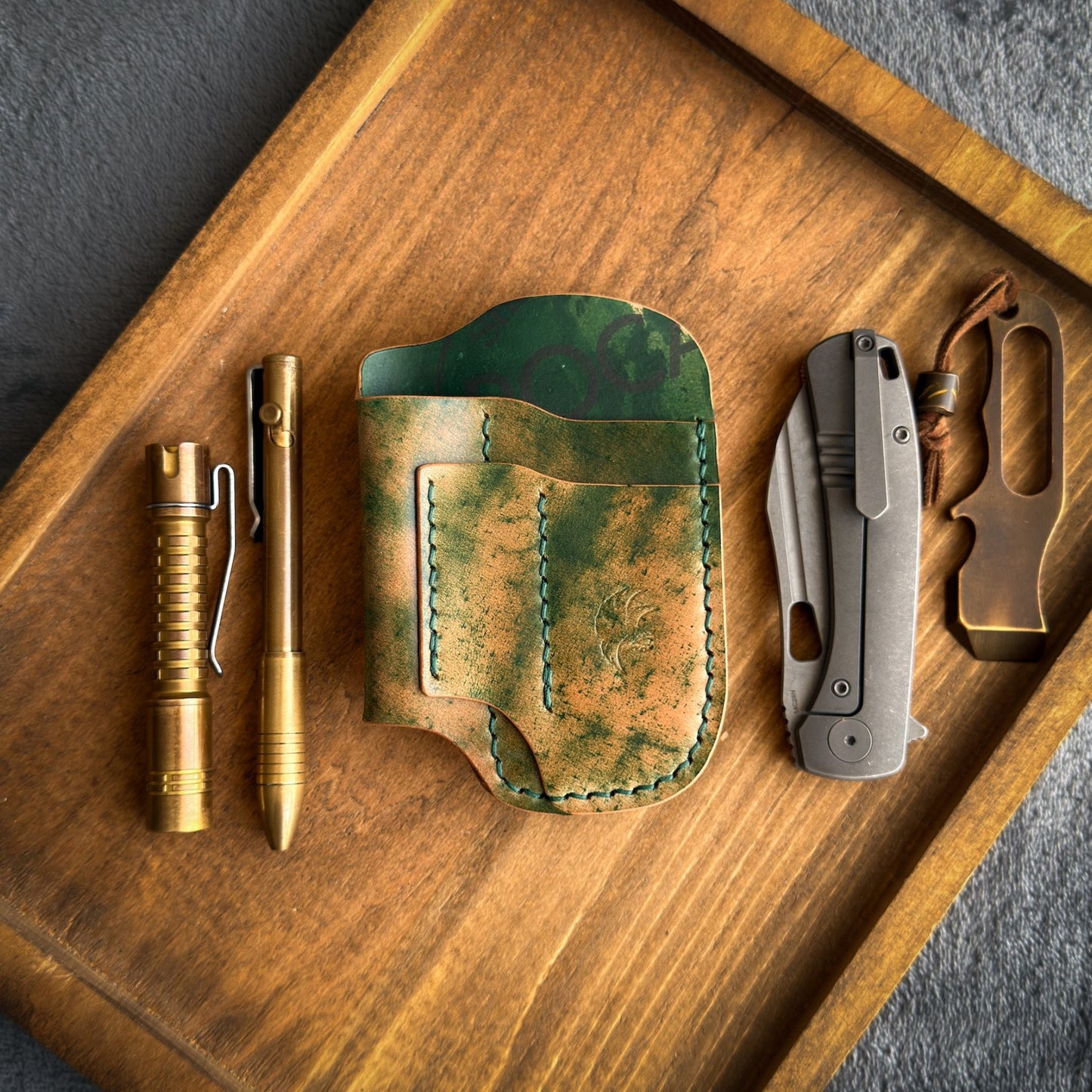 Handmade EDC pocket organizer crafted from genuine Green Marbled Rocado Shell Cordovan leather, featuring custom pockets for a folding knife, flashlight, pen, and pry bar.