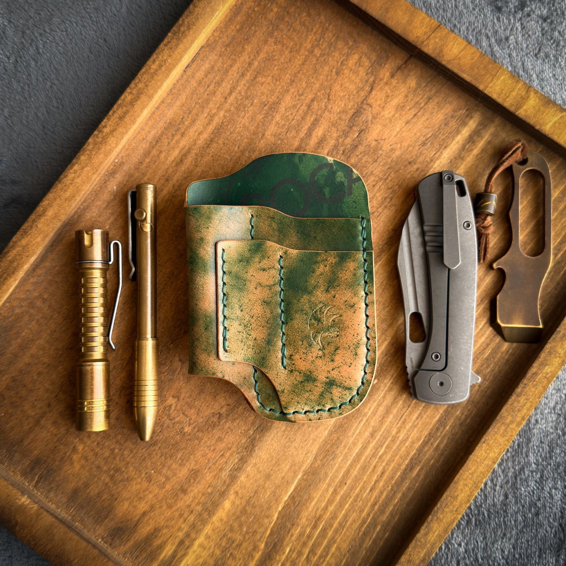 Handmade EDC pocket organizer crafted from genuine Green Marbled Rocado Shell Cordovan leather, featuring custom pockets for a folding knife, flashlight, pen, and pry bar.