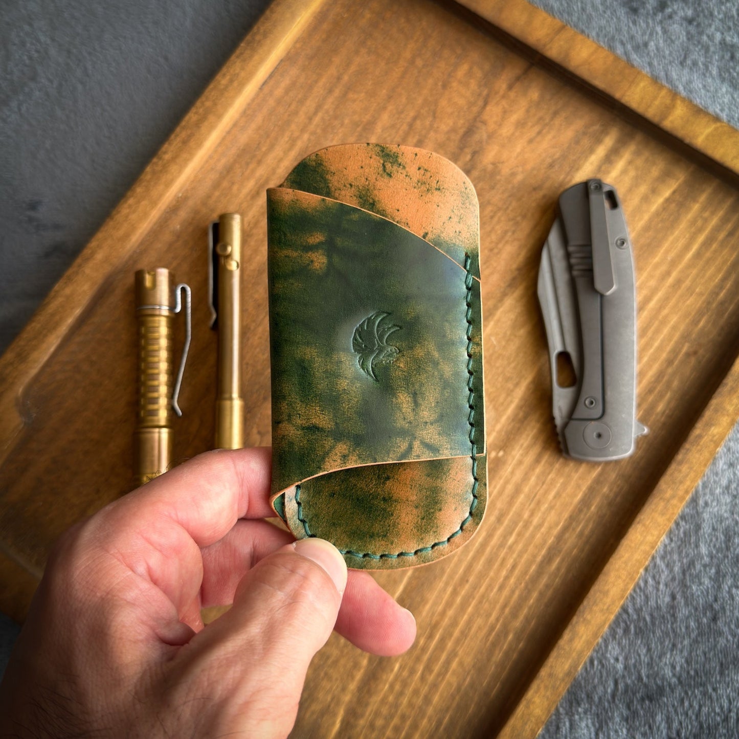 Handmade EDC pocket organizer crafted from genuine Green Marbled Rocado Shell Cordovan leather, featuring custom pockets for a folding knife, pen, and pry bar.